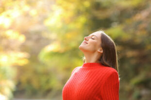 Woman outside in nature taking a deep breath in